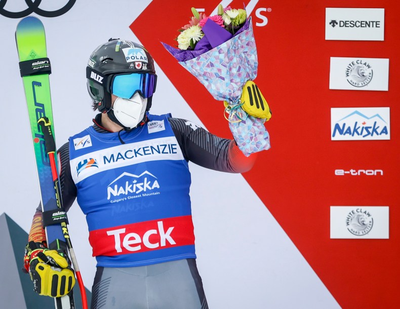 Kevin Drury des fleurs dans la mains gauche et ses skis dans la main droite.