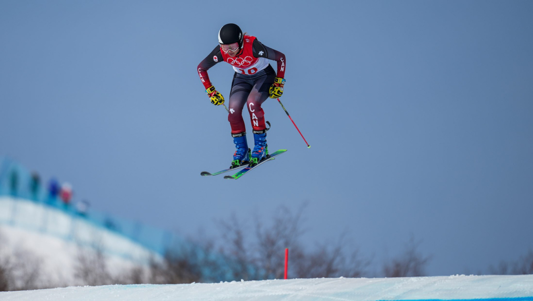 Une skieuse effectue un saut lors d'une descente de ski cross