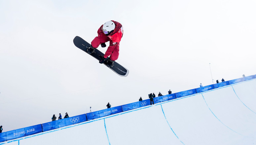 Un athlète de snowboard effectue un saut sur la demi-lune