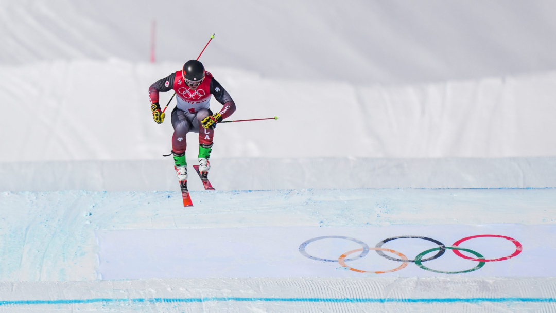 Un skieur effectue un saut lors d'une descente de ski cross