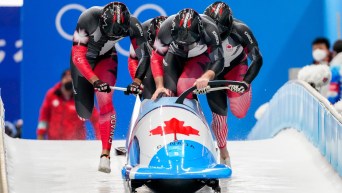 Justin Kripps, Ryan Sommer, Cam Stones et Benjamin Coakwell poussent leur bob à touter vitesse et s'apprêtent à y embarquer lors de l'épreuve de bobsleigh à quatre de Beijing 2022.