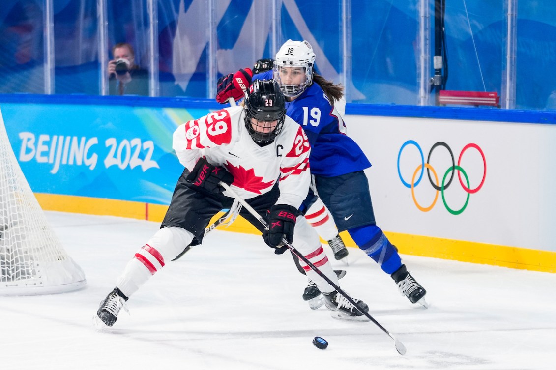 Marie-Philip Poulin d'Équipe Canada joue la rondelle contre Jincy Dunne des États-Unis à Beijing 2022.