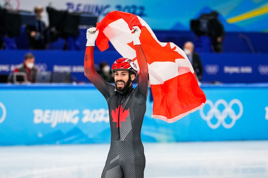 Steven Dubois agite le drapeau canadien dans les airs pour célébrer sa médaille d’argent au 1500 mètres masculin du patinage de vitesse sur courte piste à Beijing 2022