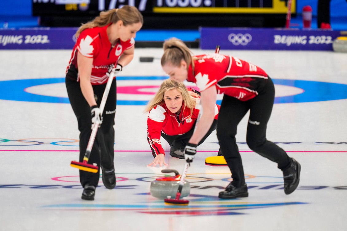 De aanvoerder van het Canadese team, Jennifer Jones, gooit een steen tijdens een wedstrijd tegen het Zuid-Koreaanse team terwijl twee van haar teamgenoten zich voorbereiden op een penseel in Peking 2022.