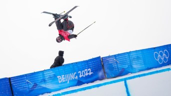 Amy Fraser tient son ski lors d'une figure dans les airs à l'épreuve de qualification en demi-lune du ski acrobatique à Beijing 2022.