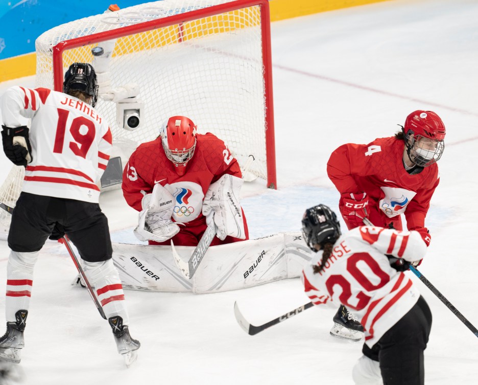 Vue de dos du but de la joueuse canadienne Sarah Nurse (20) pendant que la rondelle pénètre le haut du filet et que l'attaquante canadienne Brianne Jenner attaque le filet contre le comité olympique russe à Beijing 2022.