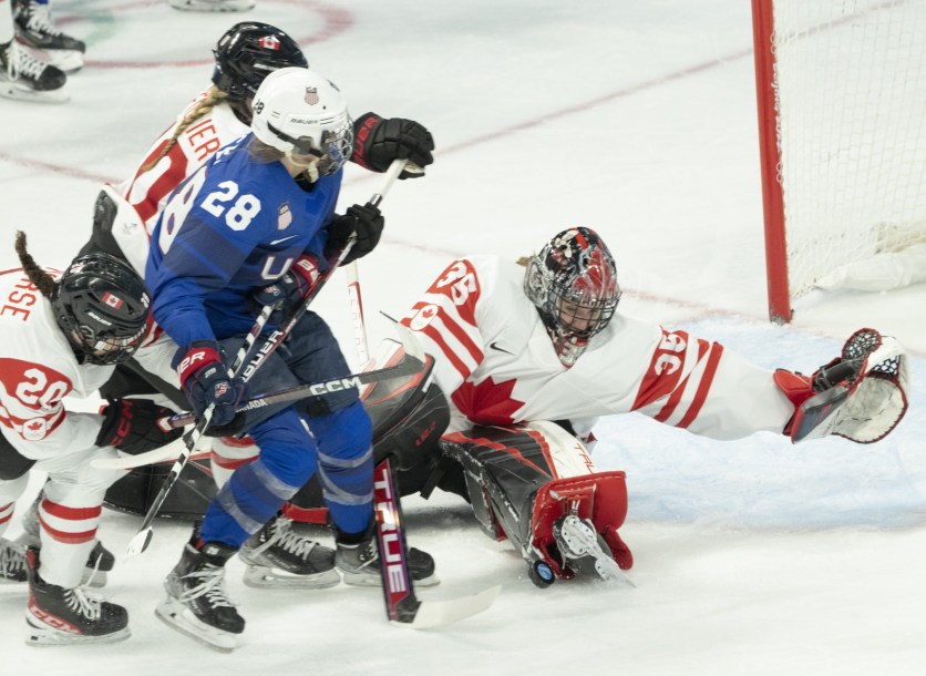 Étendue sur la patinoire, la gardienne de but d'Équipe Canada réalise un arrêt en étirant la jambière gauche face à l'américaine Amanda Kessel.