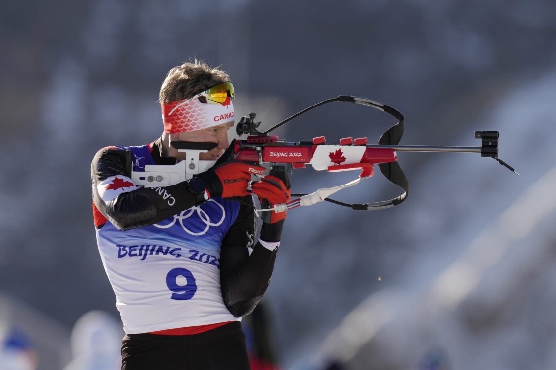 Scott Gow, l'arme à la main,  tire lors de la course individuelle masculine de 20 km au biathlon de Beijing 2022
