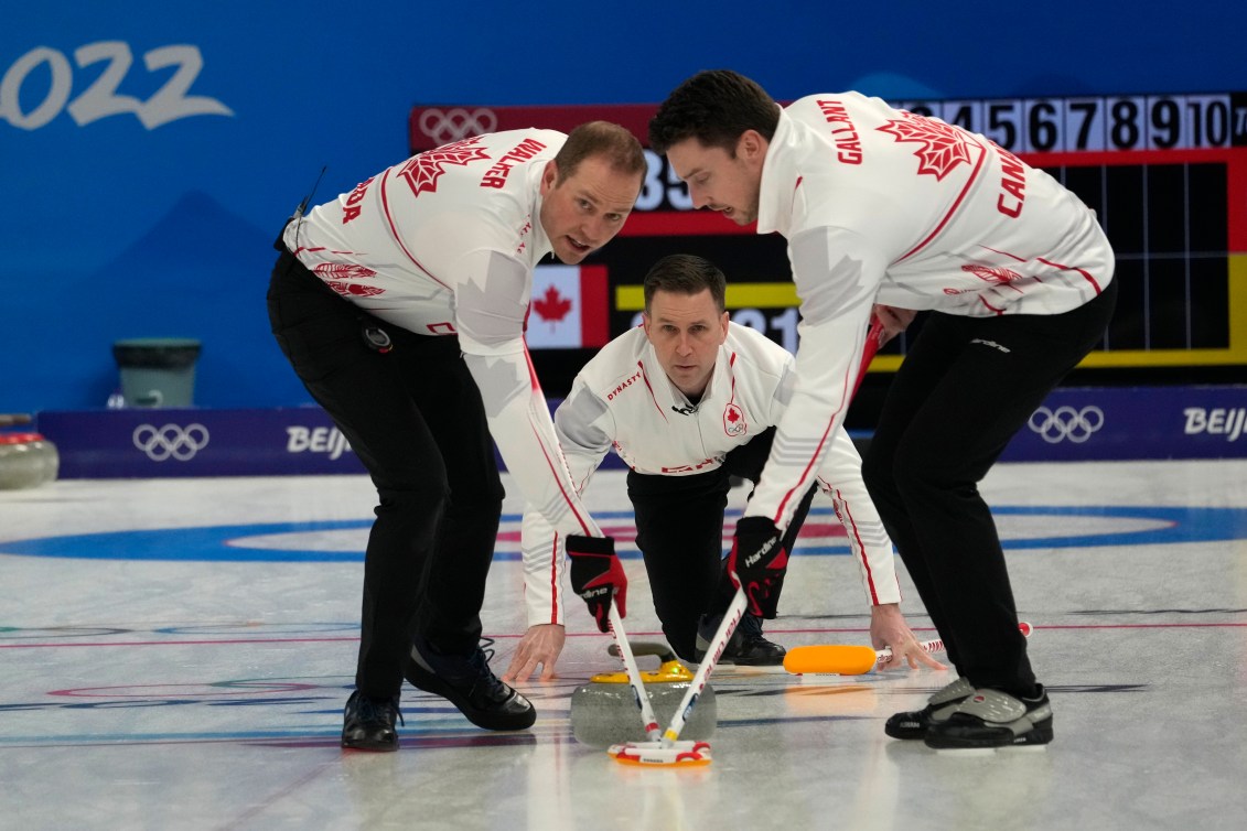 Brad Gushue retire son tir tandis que Geoff Walker et Brett Gallant balayent la glace au curling masculin contre le Danemark à Beijing 2022.