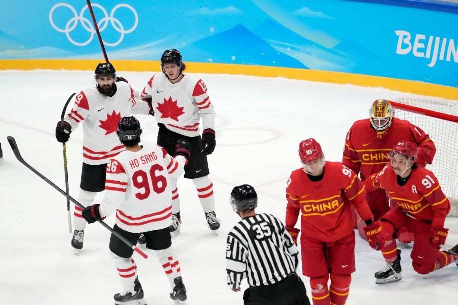 Des joueurs canadiens sur la glace devant le filet de l'équipe chinoise.