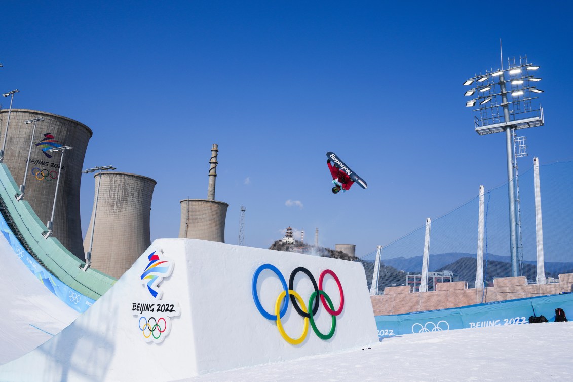 Le planchiste d'Équipe Canada Max Parrot prend sa planche dans les airs en effectuant un salto, la tête en bas, sur le big air à Beijing 2022.