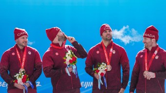 Quatre bobeurs avec leur médaille d'or au cou.