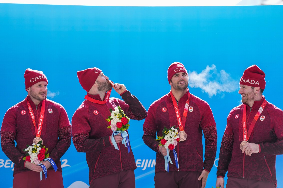 Quatre bobeurs avec leur médaille d'or au cou.