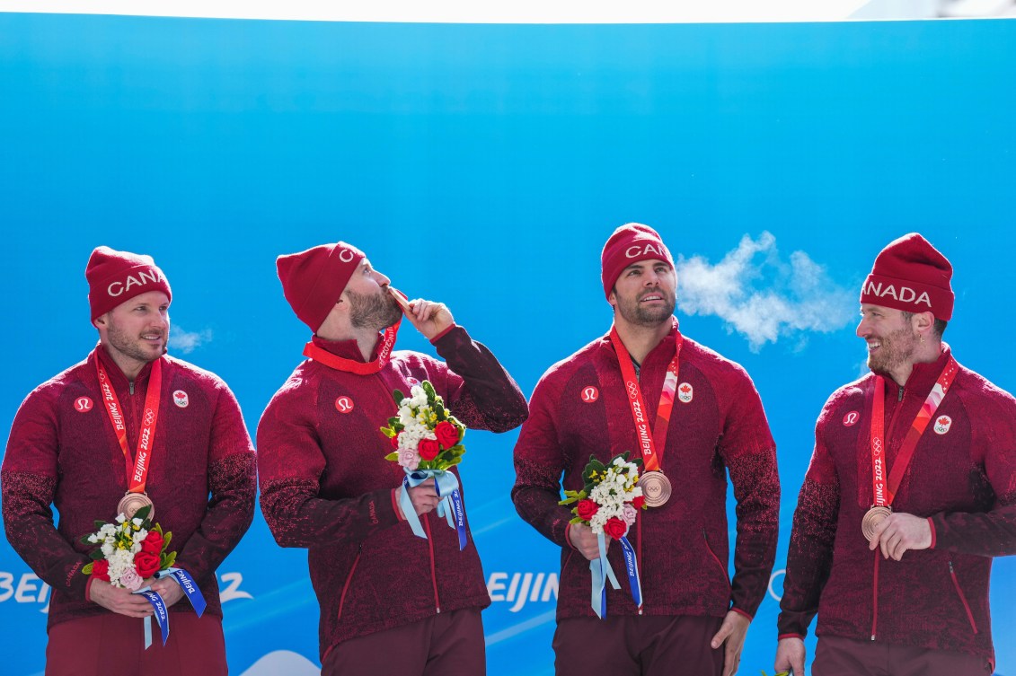 Quatre bobeurs avec leur médaille d'or au cou. 