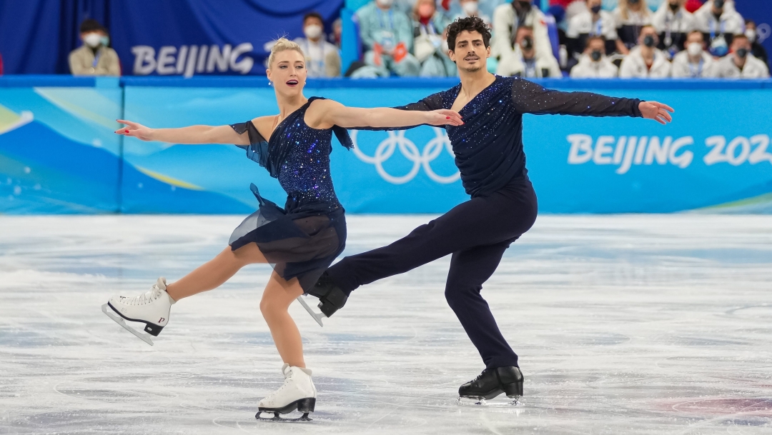 Les patineurs artistiques canadiens Piper Gilles et Paul Poirier lèent la jambe droite et écartent les bras de manière synchronisée.