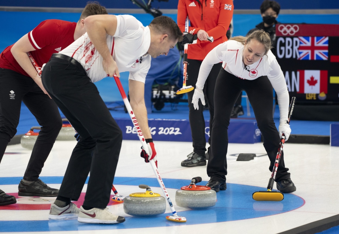 Rachel Homan regarde son coéquipier John Morris balayer une pierre.