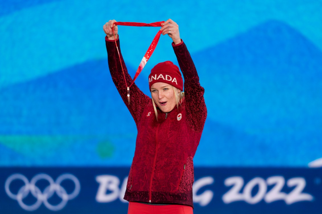 La planchiste d'Équipe Canada Meryeta O'Dine soulève sa médaille de bronze dans les airs sur le podium de snowboard cross féminin à Beijing 2022.