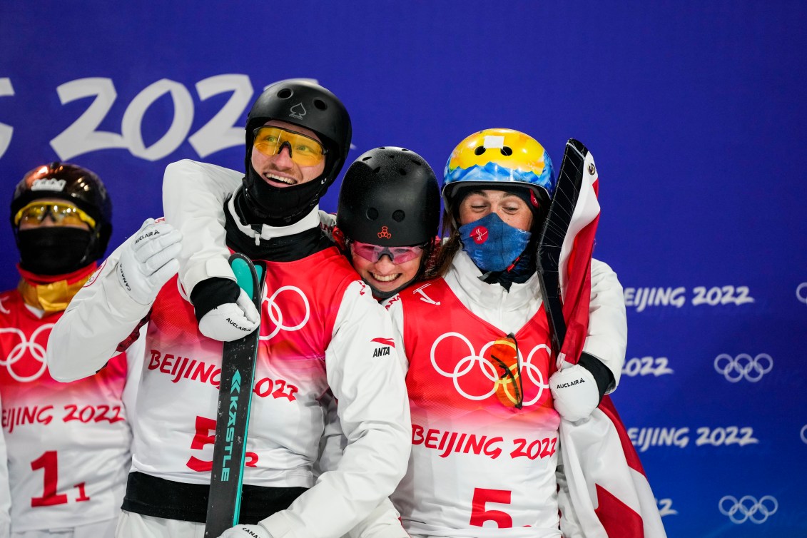 Trois skieurs acrobatiques s'enlacent par les épaules. 