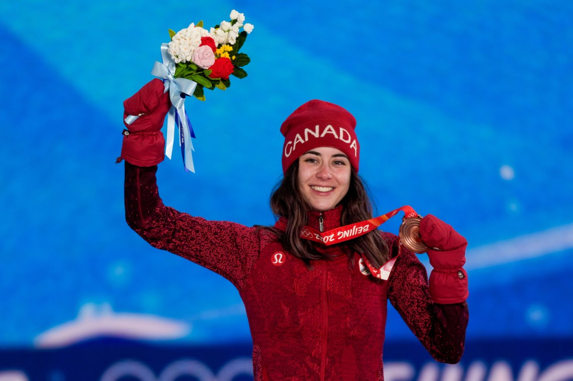 Rachael Karker sur le podium sa médaille dans la main gauche et des fleurs dans la main droite.