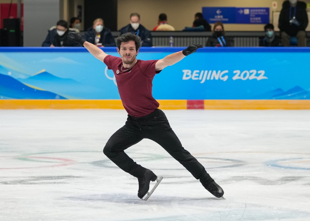 Le patineur artistique canadien Keegan Messingécarte les bras et pointe le devant de son patin droit dans la glace à une séance d'entrainement à Beijing 2022.