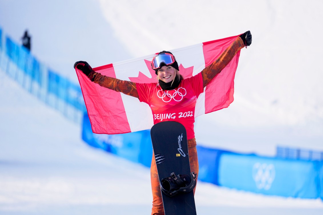 Meryeta O'Dine tient un drapeau canadien à bout de bras, sa planche à la verticale devant elle.