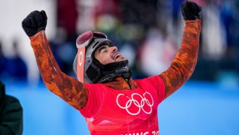 Le planchiste d'Équipe Canada Eliot Grondin lève les bras dans les airs pour célébrer sa médaille d'argent en snowboard cross masculin à Beijing 2022.