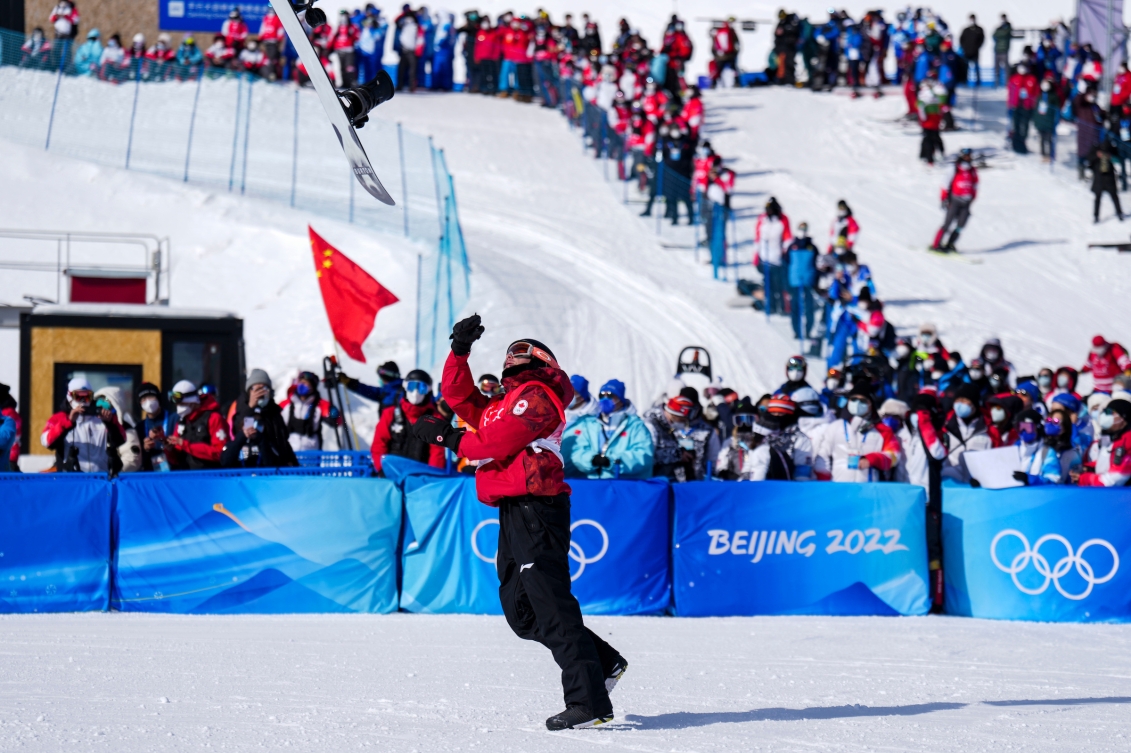 Mark McMorris lance sa planche à neige dans les airs pour célébrer sa médaille de bronze en slopestyle à Beijing 2022.