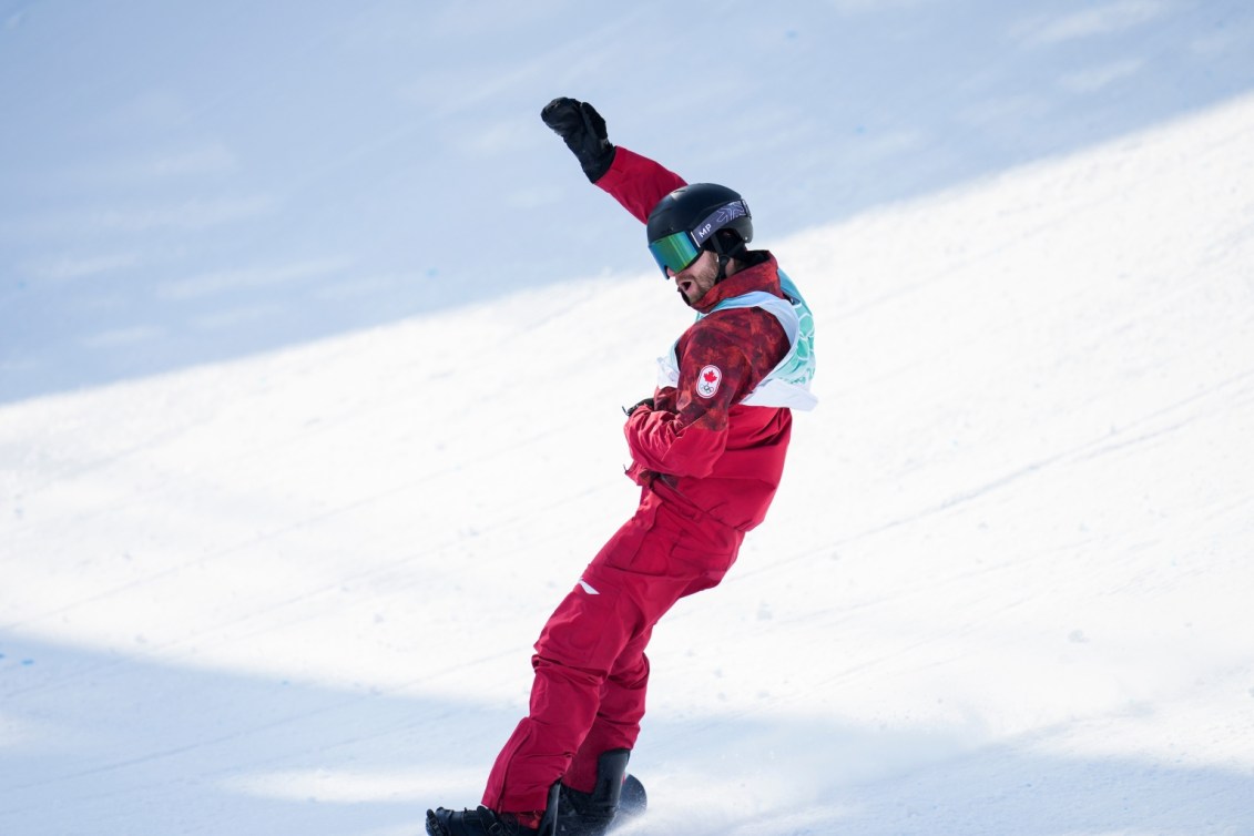 Max Parrot lève la main en l'air à la fin de sa performance au big air en snowboard pour célébrer sa médaille de bronze à Beijing 2022