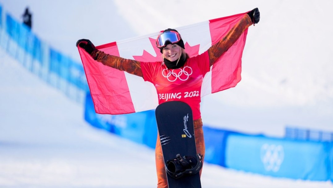 Meryeta O'Dine tient le drapeau canadien dans son dos après avoir atteint le podium du snowboard cross féminin à Beijing 2022