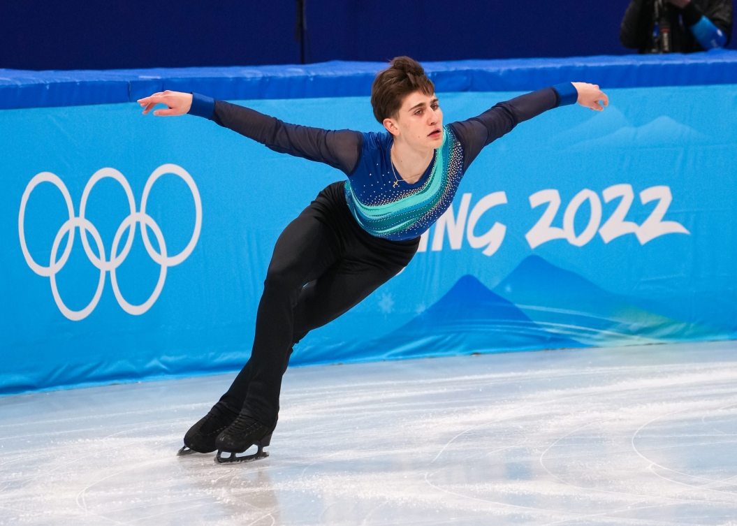 Roman Sadovsky en action sur la glace. Il porte un pantalon noir et un chandail noir avec des lignes obliques dans différents tons de bleus.