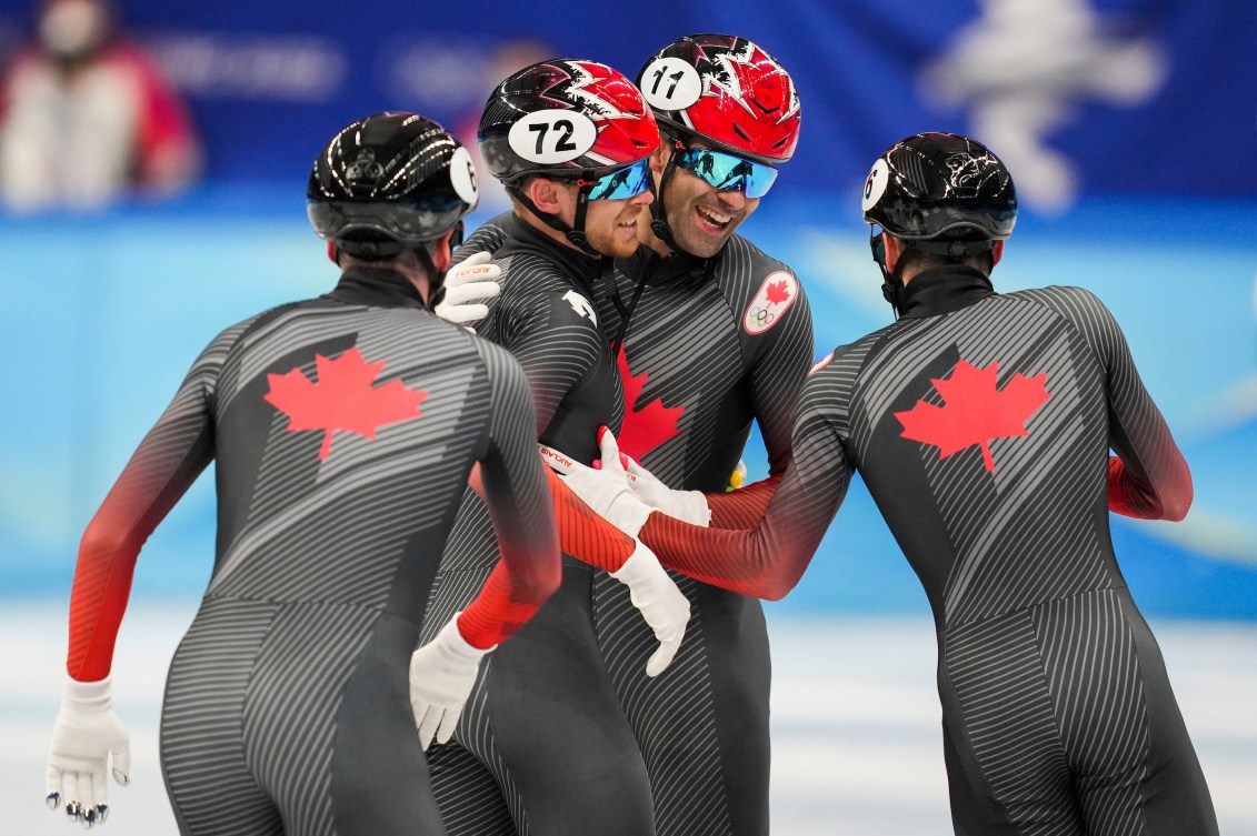 Quatre patineurs canadiens se rassemblent pour célébrer leur course. 