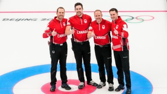 De gauche à droite, Geoff Walker, Brett Gallant, Mark Nichols et Brad Gushue lèvent le pouce et sourient, côte à côte sur la glace, après leur victoire de bronze au curling masculin à Beijing 2022