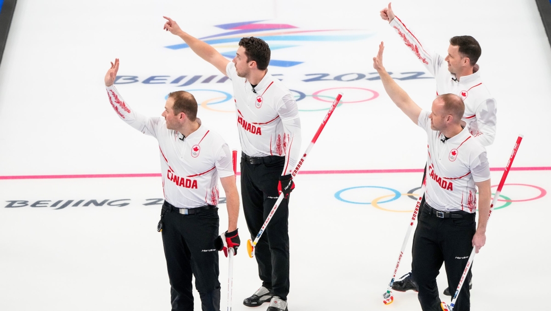Équipe Gushue envoie la main en l'air pour célébrer sa victoire contre la Norvège au curling masculin à Beijing 2022