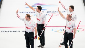 Équipe Gushue envoie la main en l'air pour célébrer sa victoire contre la Norvège au curling masculin à Beijing 2022