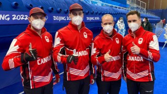 Toute l'équipe Gushue du curling masculin lève le pousse en souriant à la caméra à Beijing 2022