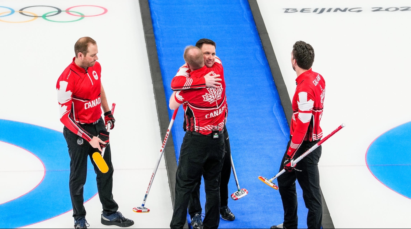 Brad Gushue serre son coéquipier de longue date, Mark Nichols, avec le sourire aux lèvres et ses autres coéquipiers à ses côtés sur la glace après avoir gagné le bronze contre les États-Unis au curling masculin à Beijing2022