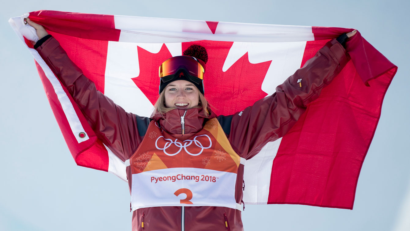 Cassie Sharpe soulève le drapeau canadien derrière elle après une victoire en ski acrobatique à PyeongChang 2018