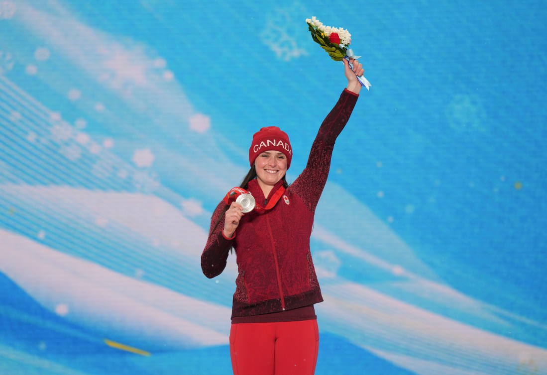 Marielle Thompson tient des fleurs à bout de bras de la main gauche et sa médaille d'argent de la main droite. 