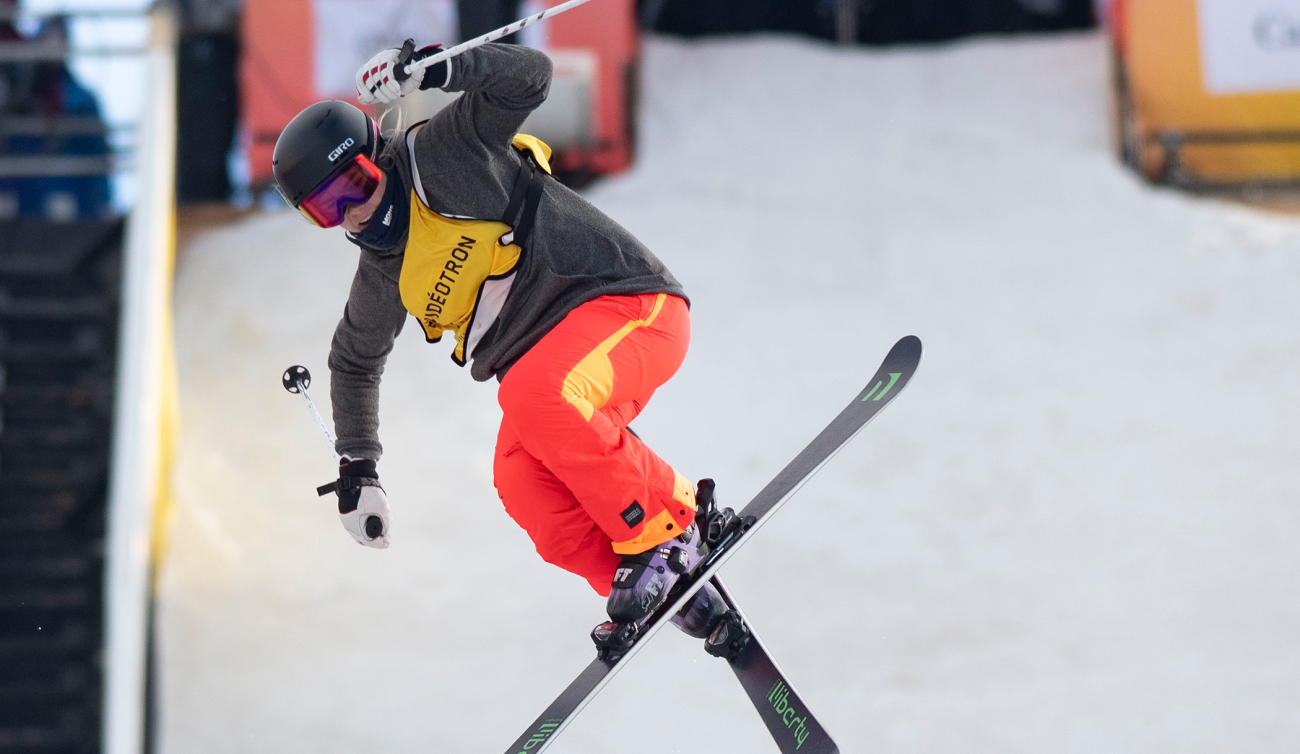 Elena Gaskell exécute une figure en croisant les skis lors d'une compétition de ski acrobatique