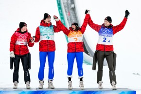 Les quatre canadiens médaillés de bronze en saut à ski à l'épreuve mixte par équipes sautent ensemble sur le podium