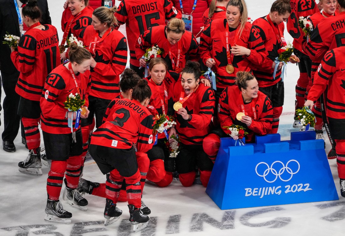 Les joueuses d'Équipe Canada, dont Sarah Nurse, regardent la médaille d'or dans leur cou, après leur victoire en hockey féminin à Beijing 2022.