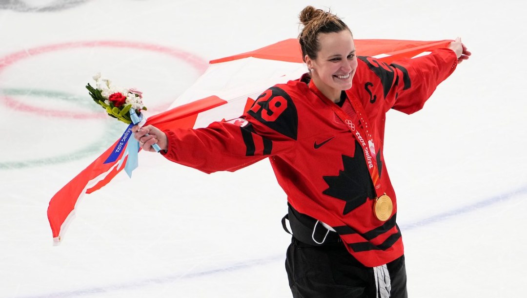 Marie-Philip Poulin d'Équipe Canada porte le drapeau dans son dos, sa médaille d'or au cou après la victoire du Canada contre les États-Unis d'Amérique en finale du hockey féminin à Beijing 2022.