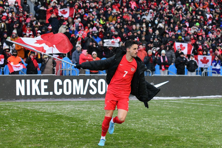 Un joueur célèbre sur le terrain avec le drapeau canadien.