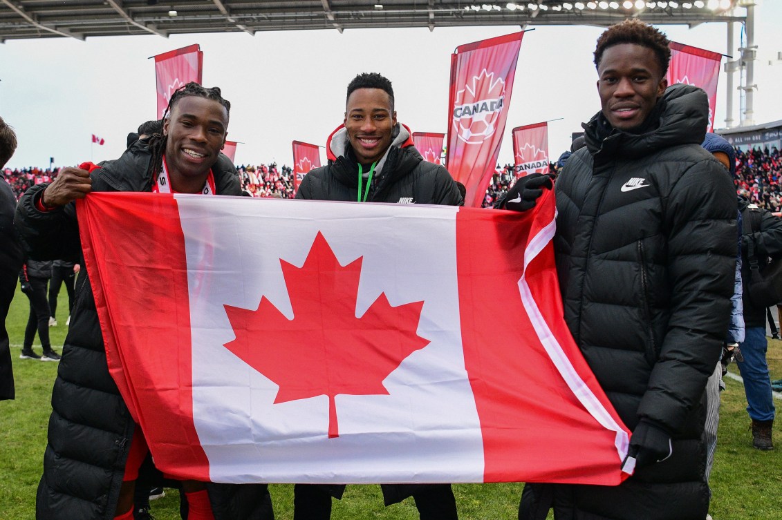 Samuel Adekugbe, Mark-Anthony Kaye et Iké Ugbo célèbre en tenant le drapeau du Canada.