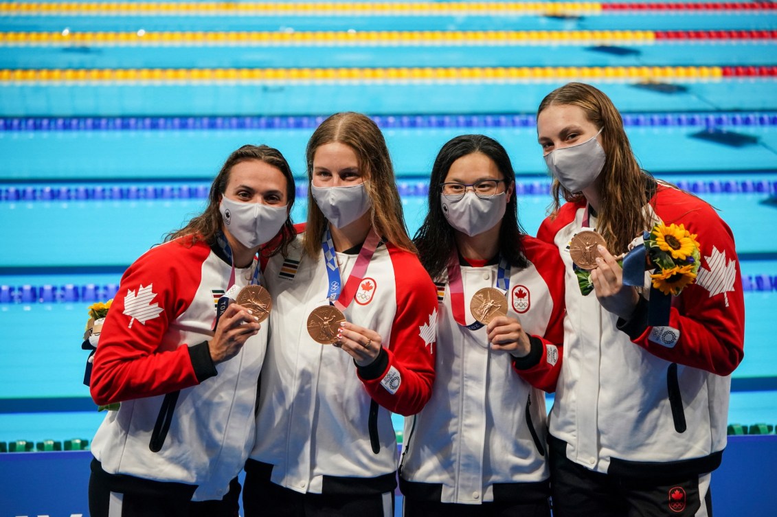 Les nageuses Kylie Masse, Sydney Pickrem, Margaret Mac Neil et Penny Oleksiak montrent leurs médailles de bronze et sourient à la caméra à Tokyo 2020