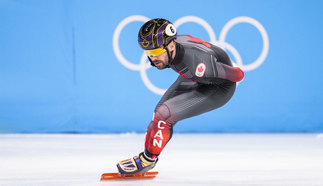 Charles Hamelin patine devant les anneaux olympiques.