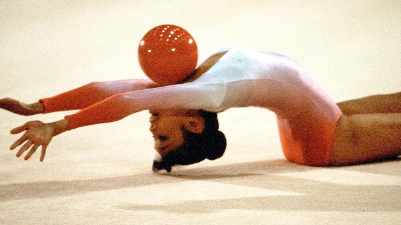 Une gymnaste rythmique fait un exercice avec un ballon. 