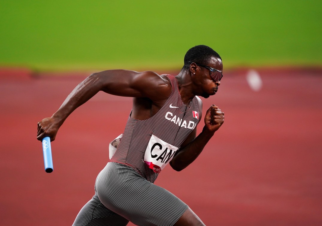 Aaron Brown corre con il bastone nella mano destra. 