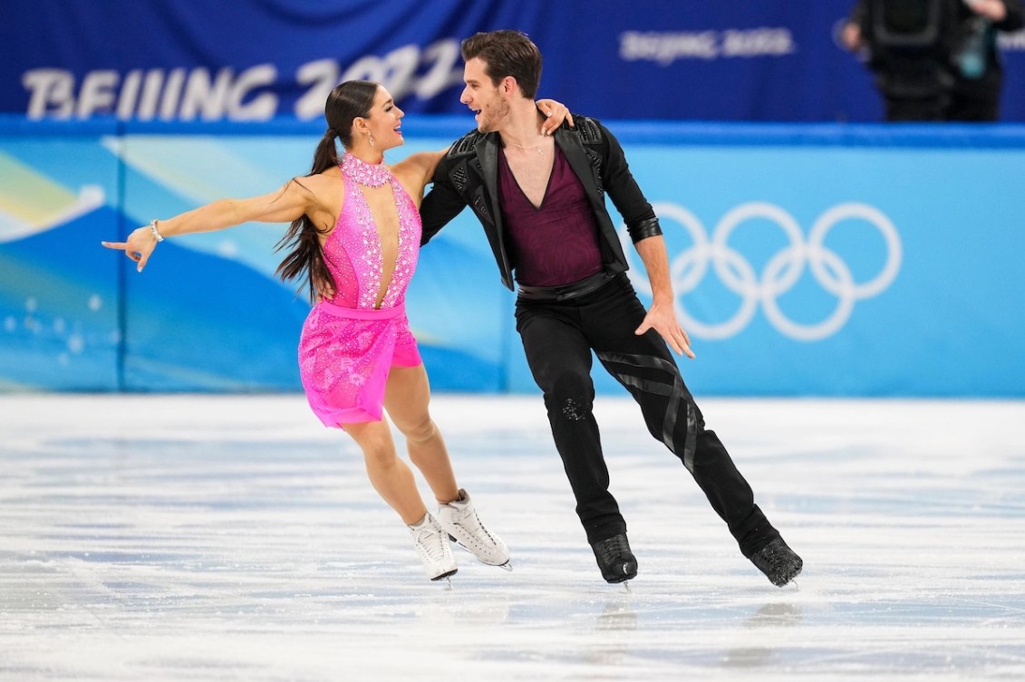 Deux patineurs artistiques performent sur la glace et se regardent dans les yeux. 