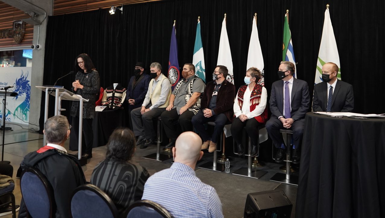 La présidente du COC Tricia Smith fait une allocution alors que les membres des Chefs des Première Nations Lilwat, Musqueam, Squamish et Tsleil-Waututh. de même que les maires de Vancouver et Whistler sont devant le public en décembre 2021.